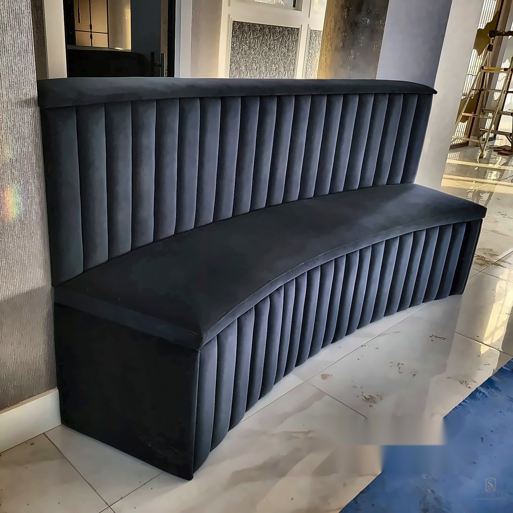 Bespoke fluted black velvet curved bench in a marble entryway